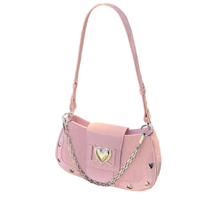 Pink handbag with decorative chain and heart emblem held by a hand on a textured surface.